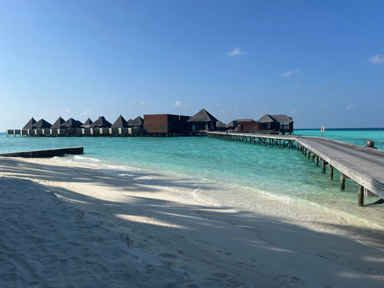 Maldives resort with a white-sand beach, overwater villas and a wooden jetty