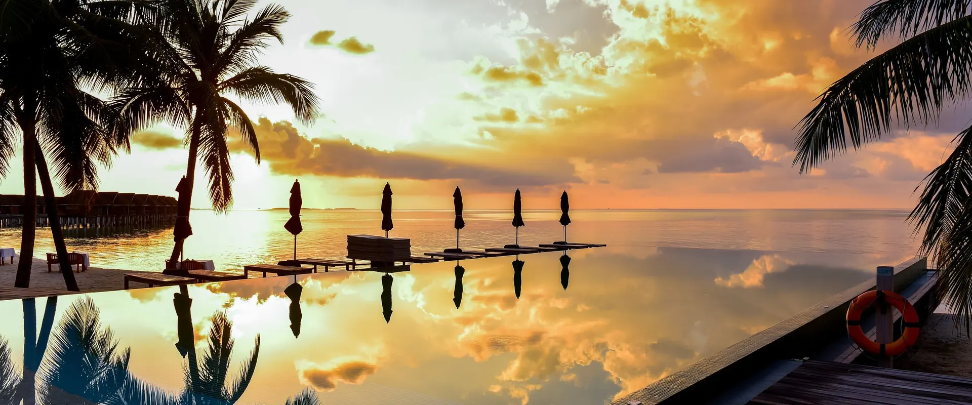 Overwater villas in the Maldives at sunset reflected in a calm lagoon