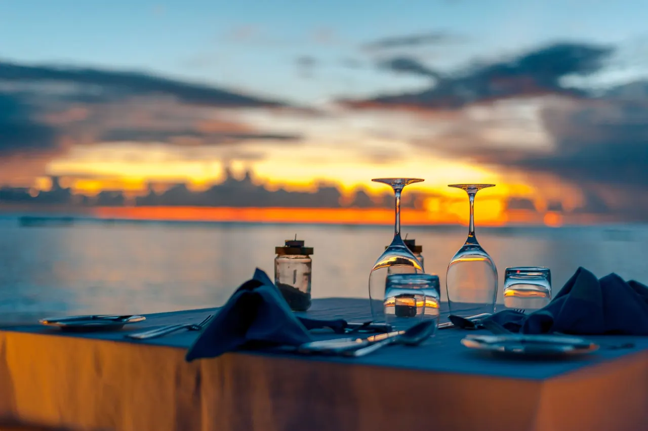 Private candlelit dinner table set up on a Maldives beach at sunset