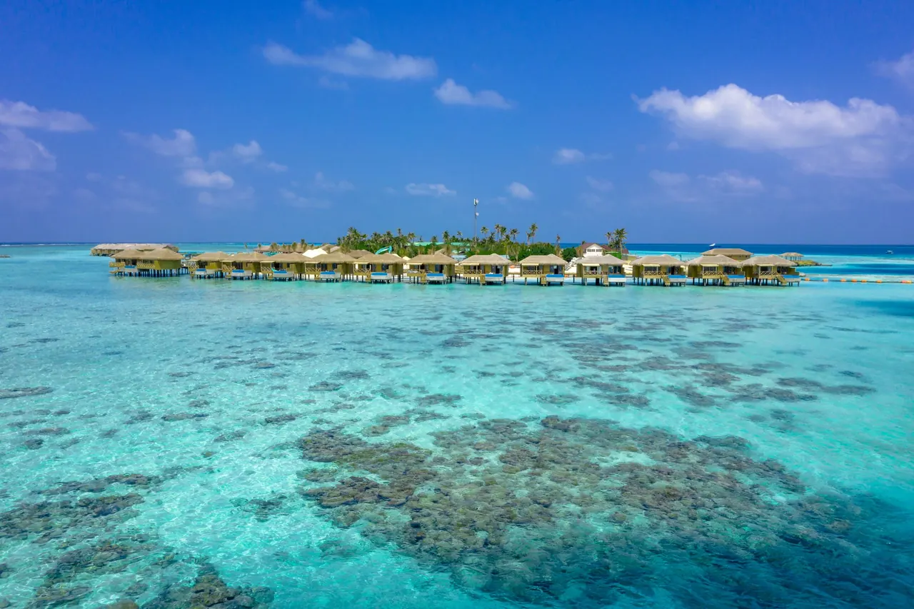 Aerial view of Maldives overwater villas above a coral reef and turquoise lagoon