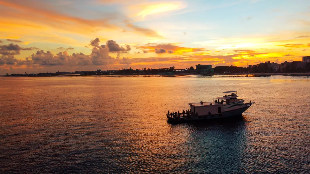 Boat cruising across calm water at sunset in the Maldives