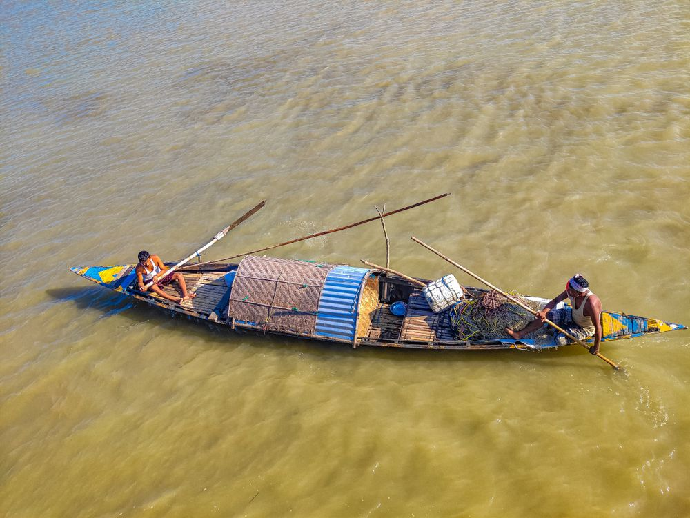Fishermen navigating a wooden boat on the Brahmaputra near Majuli, Assam